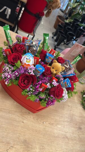 Kalp biçimli kırmızı kutuda gül, mor çiçekler ve paketli çikolata aranjmanı